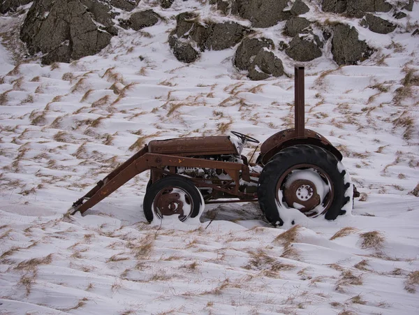 Ein alter Traktor auf einer verschneiten Wiese — Stockfoto