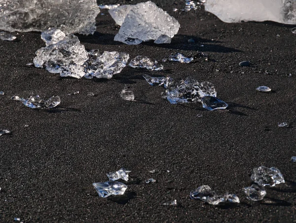 Kleine Eisbrocken funkeln auf dem schwarzen Sand — Stockfoto