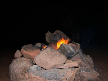 Taştan bir şöminede küçük bir kamp ateşi.