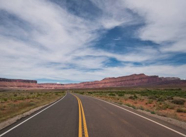 Arka planda güzel dağ manzaralı asfalt bir yol.