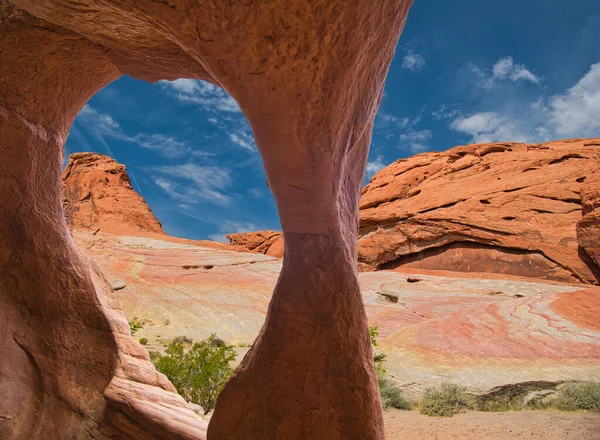 The view of the colourful rocks and plants through a large rock hole