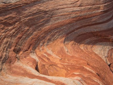 Renkli çizgileri ve kumdaki bazı izleri olan dalgalı kayalar.