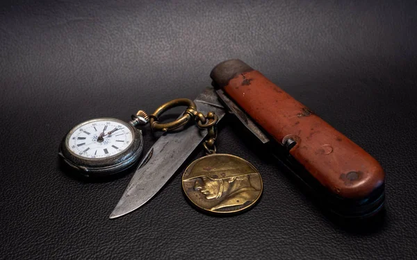 vintage antique military pocket knife with pocket clock and soldier emplem black background world war 2 leather surface
