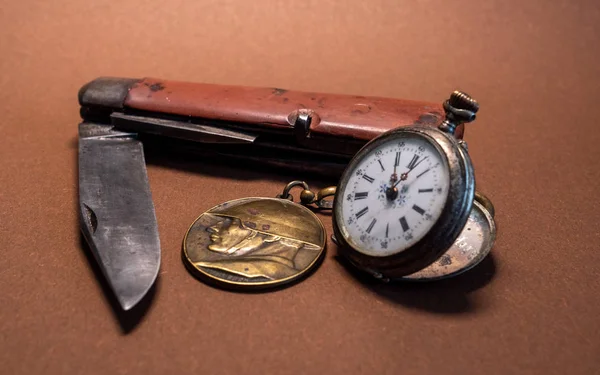vintage antique military pocket knife with pocket clock and soldier emplem brown background world war 2 old
