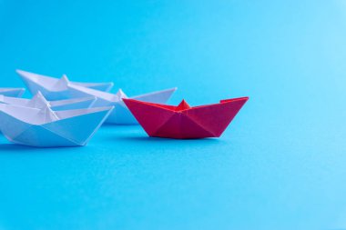 Beyaz ve kırmızı kağıt tekne veya gemi mavi zemin üzerine bir yönde. İş için seçici odak konseptiyle yenilikçi çözüm