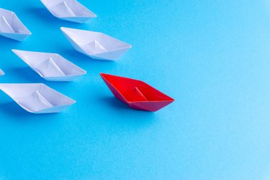 Beyaz ve kırmızı kağıt tekne veya gemi mavi zemin üzerine bir yönde. İş için seçici odak konseptiyle yenilikçi çözüm