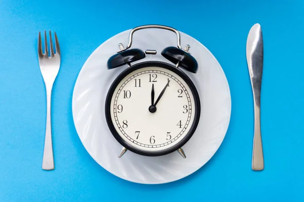 Alarm clock with fork and knife on the table. Time to eat, Breakfast, Lunch time and dinner concept.