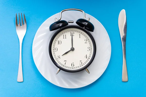 テーブルの上のナイフとフォークの目覚まし時計 時間を食べる 昼食の時間と夕食の概念 — ストック写真