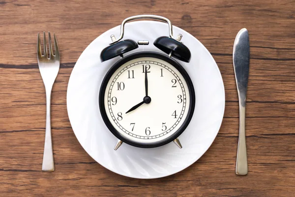 Çalar saat çatal ve bıçak masanın üzerinde. Yemek, Kahvaltı, akşam yemeği ve zaman kavramı öğle yemeği vakti.