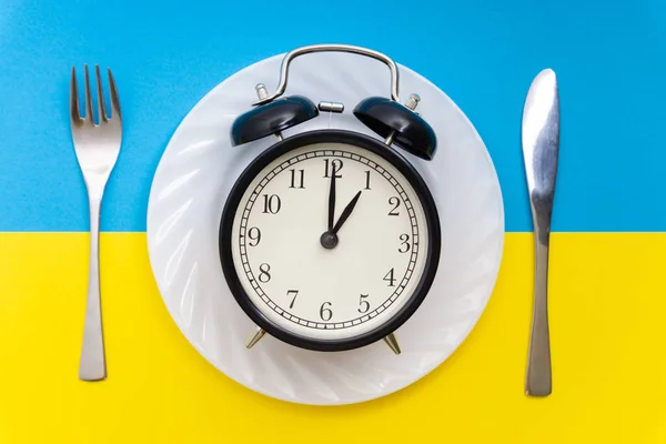 Alarm clock with fork and knife on the table. Time to eat, Breakfast, Lunch time and dinner concept.