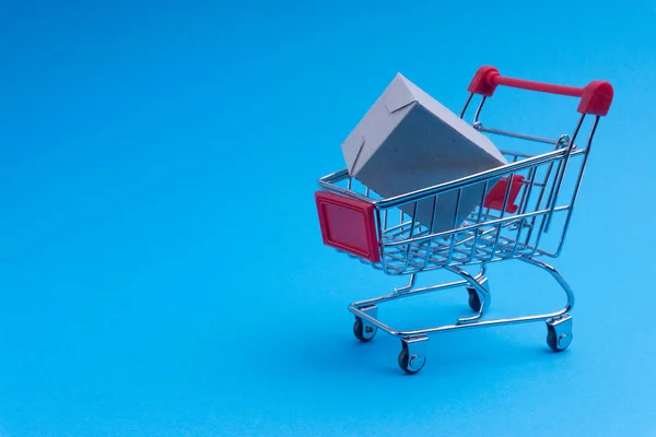 Shopping cart and box on blue background, business and shopping concept. Selective focus