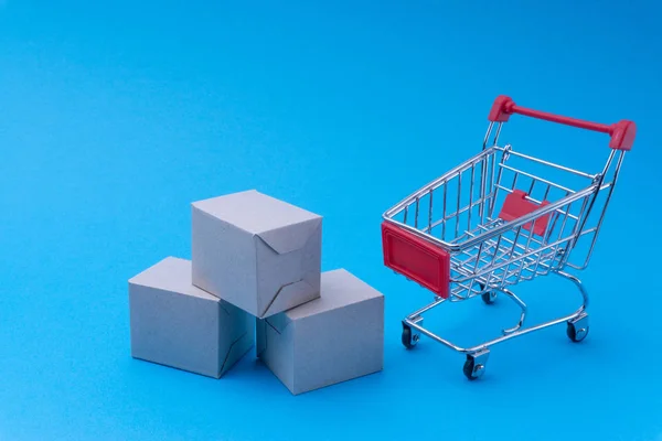 Shopping cart and box on blue background, business and shopping concept. Selective focus