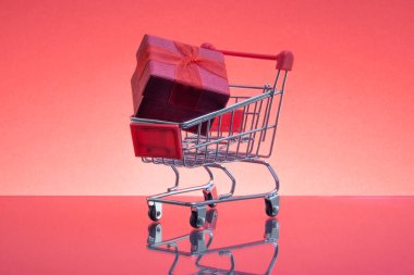 Alışveriş sepeti ve hediye kutu kırmızı arka plan, iş ve kutlama kavramı. Seçici odak