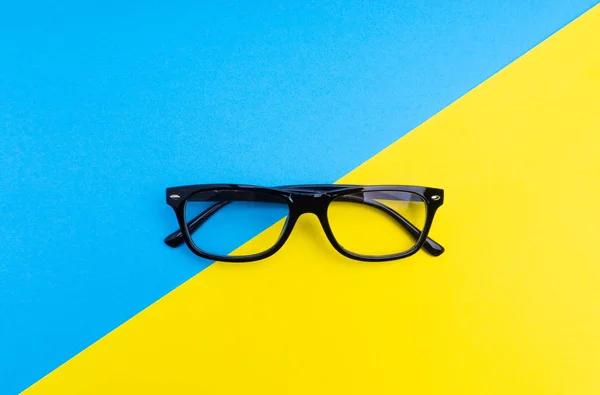 Black frame eyeglasses on blue and yellow background