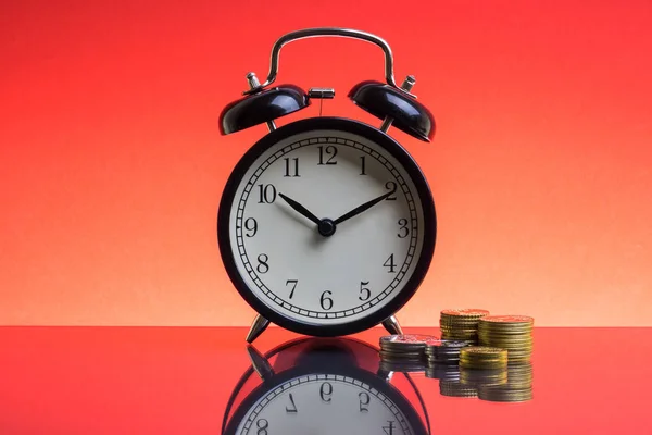 Reloj Despertador Monedas Sobre Fondo Rojo Con Enfoque Selectivo Fragmento Imagen de archivo