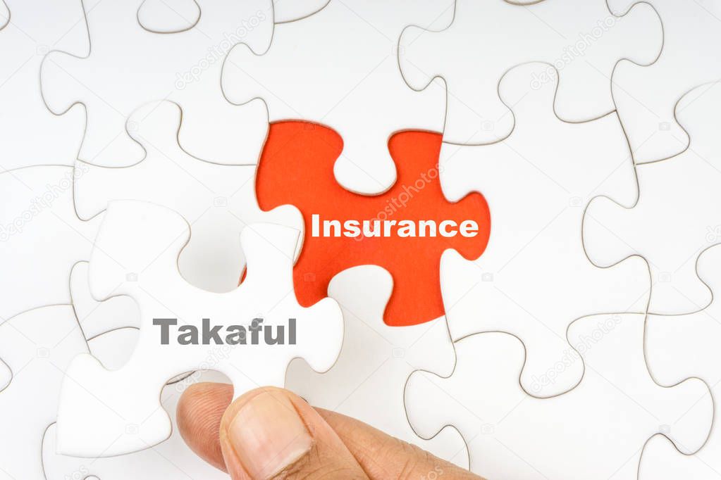 Hand holding piece of jigsaw puzzle with word TAKAFUL INSURANCE. Selective focus