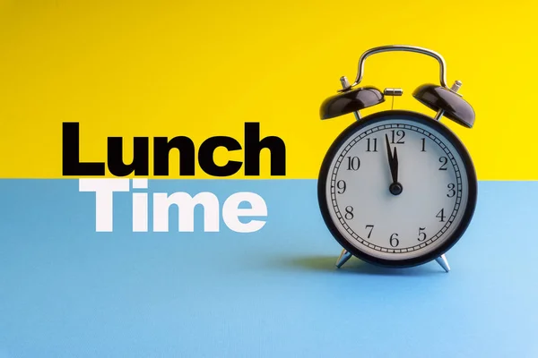 LUNCH TIME inscription written on Alarm Clock on blue yellow background. Business and motivation concept