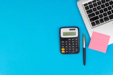 Düz yatıyordu, üst görünüm ofis masa masası. Hesap makinesi, siyah kalem, turqoise mavi arka planda dizüstü bilgisayar ile çalışma alanı. İş finansmanı, eğitim teknolojisi ve metin konsepti için Copy Space