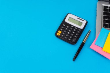 Düz yatıyordu, üst görünüm ofis masa masası. Hesap makinesi, siyah kalem, turqoise mavi arka planda dizüstü bilgisayar ile çalışma alanı. İş finansmanı, eğitim teknolojisi ve metin konsepti için Copy Space
