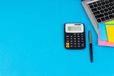 Düz yatıyordu, üst görünüm ofis masa masası. Hesap makinesi, siyah kalem, turqoise mavi arka planda dizüstü bilgisayar ile çalışma alanı. İş finansmanı, eğitim teknolojisi ve metin konsepti için Copy Space