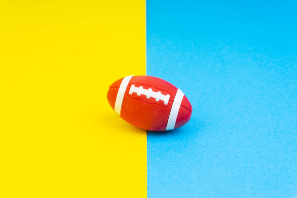 Регби мяч на синем и желтом фоне. Селективный фокус
