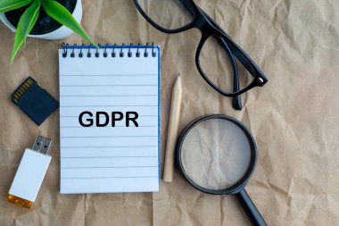 Not defteri, çiçek vazo, gözlük, depolama kartı, kalem, büyüteç ve ahşap kağıt arka plan üzerinde kelimeler Gdpr. İş, eğitim ve kopyalama alanı kavramı