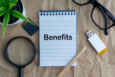 Not defteri, çiçek vazo, gözlük, saklama kartı, kalem, büyüteç ve ahşap kağıt arka plan üzerinde faydaları kelimeler. İş, eğitim ve kopyalama alanı kavramı