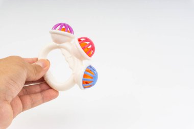 Eller beyaz arka planda çıngıraklı oyuncak veya bebek oyuncak tutun. Seçici odaklama