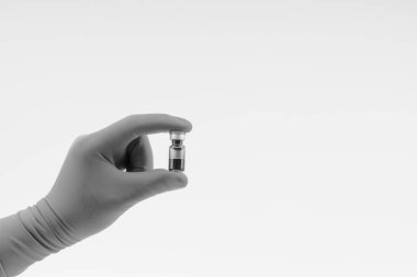 Siyah beyaz üzerinde tıbbi şişe tutan mavi bir eldiven el