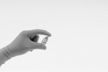 Siyah beyaz üzerinde tıbbi şişe tutan mavi bir eldiven el