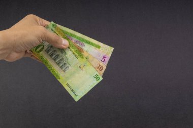 El siyah arka plan üzerinde Suudi Riyal banka notları tutarak. Finansal kavram ve seçici odak