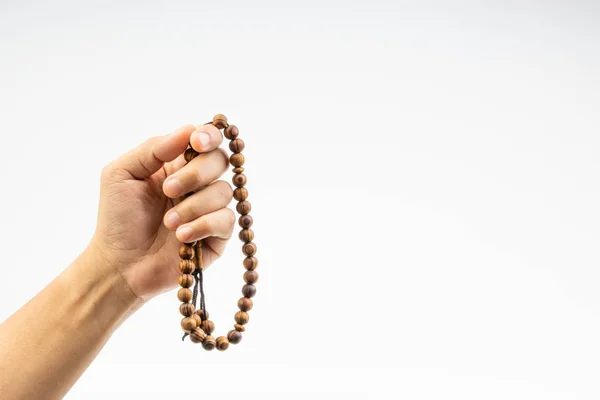 Hand holding a muslim rosary beads or Tasbih on white background. Copy space and selective focus