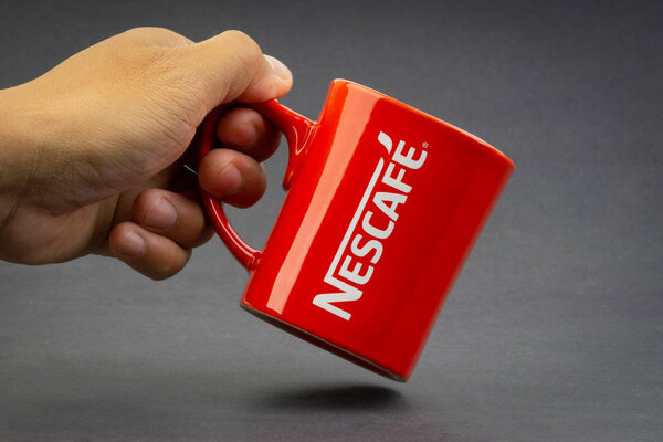 Kuala Lumpur, Malaysia - July 03, 2019 : Promotional red Nescafe mug on dark background. Selective focus