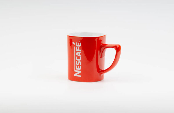Kuala Lumpur, Malaysia - July 03, 2019:  Promotional red Nescafe mug on white background. Selective focus