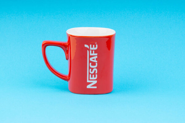 Kuala Lumpur, Malaysia - July 03, 2019:  Promotional red Nescafe mug on blue background. Selective focus