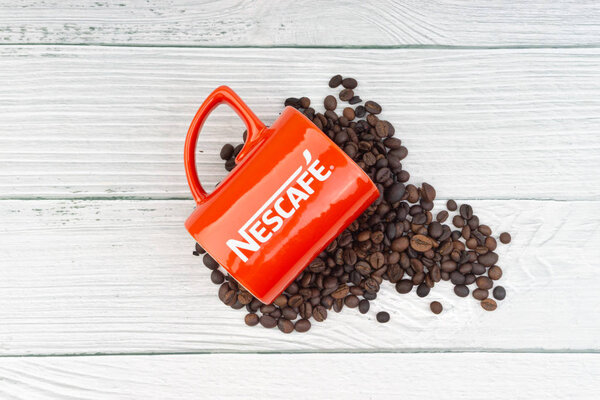 Kuala Lumpur, Malaysia - July 03, 2019: Promotional red Nescafe mug on wooden background. Selective focus