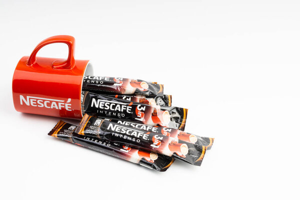 Kuala Lumpur, Malaysia - July 2, 2019: Sachet of instant Intenso Nescafe coffee with Nescafe mug on white background. Selective focus