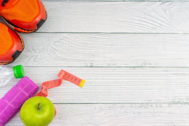 Ahşap arka plan üzerinde kopya alanı ile havlu, su, elma meyve ve spor ayakkabı üst veya düz yatıyordu görünümü. Sağlıklı bir kavram. Seçici odaklama.