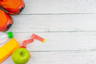 Ahşap arka plan üzerinde kopya alanı ile havlu, su, elma meyve ve spor ayakkabı üst veya düz yatıyordu görünümü. Sağlıklı bir kavram. Seçici odaklama.