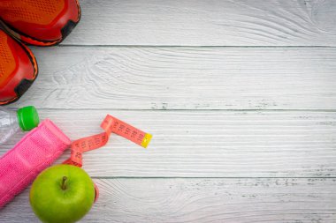 Ahşap arka plan üzerinde kopya alanı ile havlu, su, elma meyve ve spor ayakkabı üst veya düz yatıyordu görünümü. Sağlıklı bir kavram. Seçici odaklama.