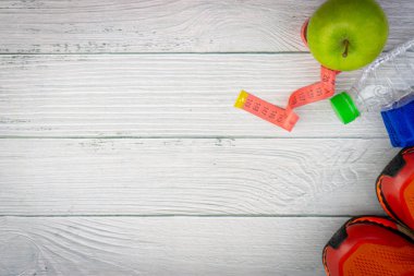Ahşap arka plan üzerinde kopya alanı ile havlu, su, elma meyve ve spor ayakkabı üst veya düz yatıyordu görünümü. Sağlıklı bir kavram. Seçici odaklama.