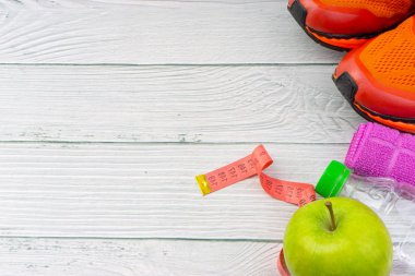 Ahşap arka plan üzerinde kopya alanı ile havlu, su, elma meyve ve spor ayakkabı üst veya düz yatıyordu görünümü. Sağlıklı bir kavram. Seçici odaklama.