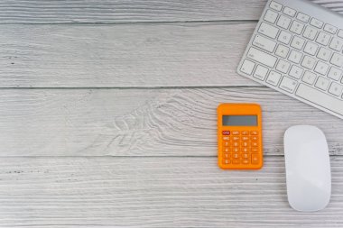 Düz yatıyordu, üst görünüm ofis masa masası. Ahşap arka planda fare, hesap makinesi ve klavye ile çalışma alanı. İş finansmanı, eğitim, teknoloji ve kopya alanı konsepti