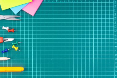 Bıçak kesici, kalem, makas ve beyaz yeşil kesme paspas arka plan üzerinde sabit. Seçici odaklama ve kopyalama alanı