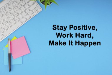 Düz yatıyordu, üst görünüm ofis masa masası. Mavi arka plan üzerine klavye, kalem ve yapışkan notlar ile yazılmış Stay Positive Work Hard Make It Happen yazımı ile Çalışma Alanı. İş, Sigorta ve motivasyon konsepti