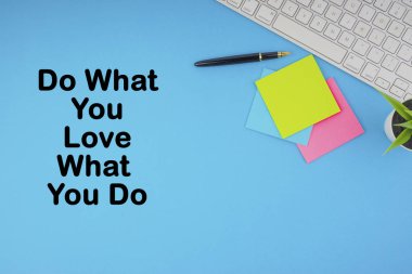 Düz yatıyordu, üst görünüm ofis masa masası. Mavi arka plan üzerine klavye, kalem ve yapışkan notlarla yazılmış Do What You Love What You Do yazıtlı çalışma alanı. İş, Sigorta ve motivasyon konsepti