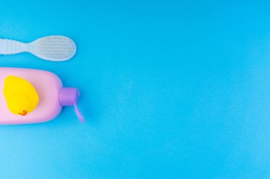 Mavi bir arka plan üzerinde bebek bakım ürünleri Düz yatıyordu kompozisyon. Şampuan veya duş şişesi jel, temizlik fırçası ve sarı kauçuk oyuncak ördek yukarıdan görünümü