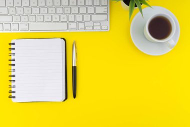 Ofis masa masasının düz görünümü. Sarı arka plan üzerinde klavye, kalem, kitap, kahve ve dekorasyon çiçek ile Çalışma alanı. Boşluk kopyalama konsepti