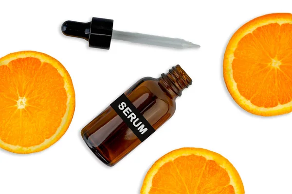 Kozmetik şişesinde C vitamini serumu, beyaz arka planda dilimlenmiş portakal. Sağlık hizmeti kavramı