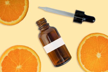 Kozmetik şişesinde C vitamini serumu, beyaz arka planda dilimlenmiş portakal. Sağlık hizmeti kavramı
